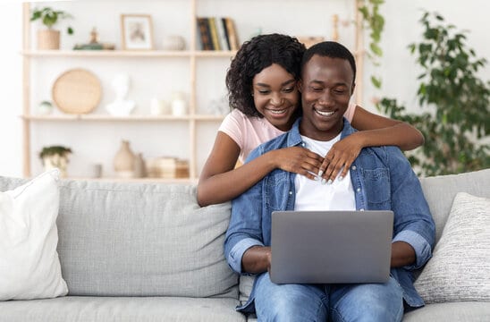 Loving african american couple using laptop together at home