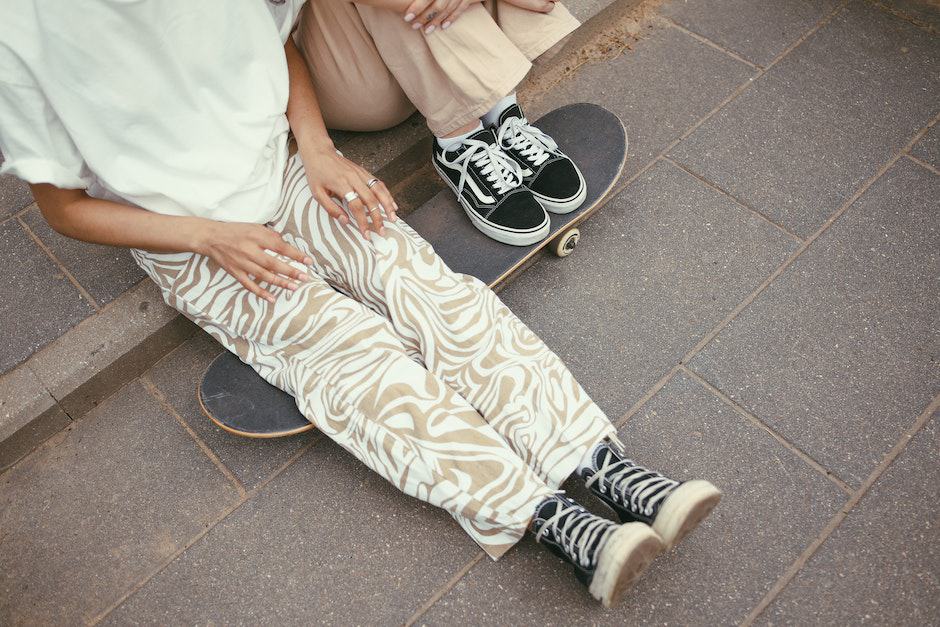 Persons Sitting on Paved Floor and a Skateboard