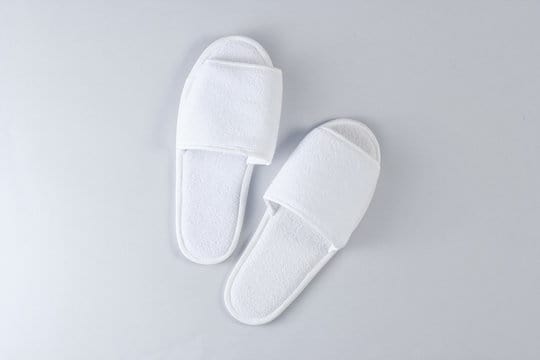 White hotel sleeping slippers on a gray background. Top view