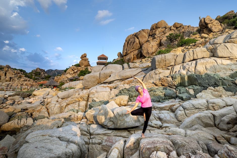 Woman in Pink Tank Top and Black Leggings Doing Yoga on Rock Formation