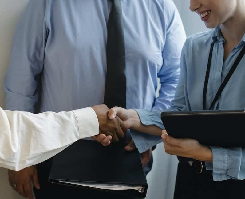 Anonymous colleagues shaking hands and smiling after meeting