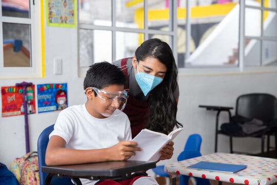 Mexican young teacher with student at school wearing face mask after coronavirus pandemic