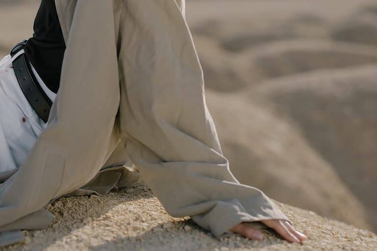 Person in Beige Coat Sitting on Sand
