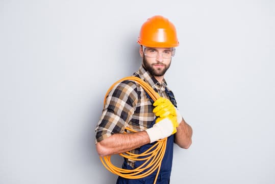 Portrait of trendy virile electrician in hardhat, overall, shirt is ready for work, having, holding 
