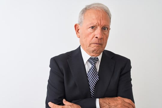 Senior grey-haired businessman wearing suit standing over isolated white background skeptic and nerv