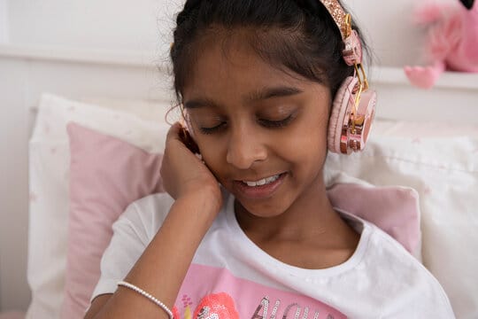 UK, London, Close-up of girl with headphones sitting on bed