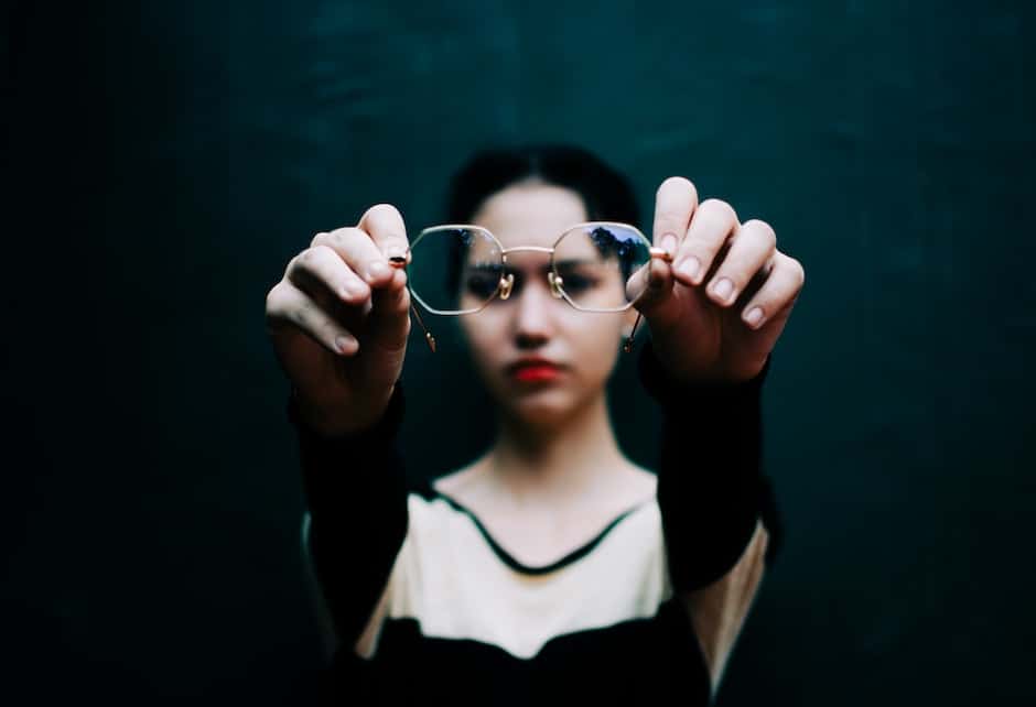 Young woman showing stylish eyewear against black wall